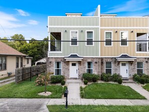 A multi-story residential building with a front yard, a mailbox, and a clear sky.