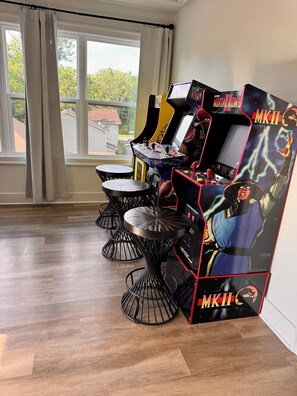 A room with a window, a table, and two arcade machines.