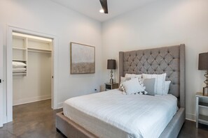 A bedroom with a large bed, a wardrobe, and a bedside table with a lamp.