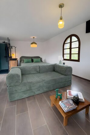 A modern living room with a green sectional sofa, a wooden coffee table, and a large window with a view.