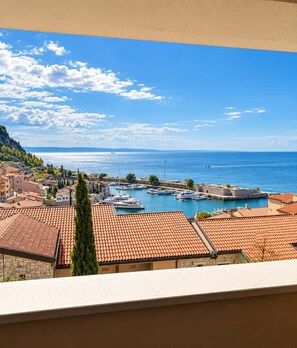 A coastal town with a marina, terracotta-roofed buildings, and a clear blue sky. - Levante - Portopiccolo Apartments (Sistiana)