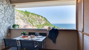 Un balcón con una mesa dispuesta para dos, con vistas a un paisaje costero.