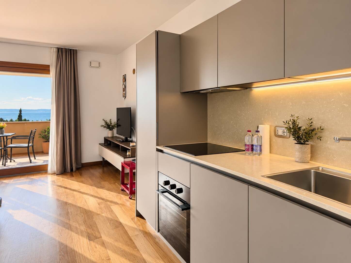 Eine moderne Küche mit Backofen, Spüle und Essbereich inklusive Tisch und Stühlen.