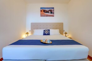 Un letto rifatto con cura, una coperta blu, un cuscino decorativo e un vassoio con tazze e teiera.