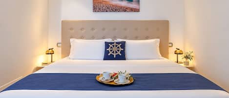 A neatly made bed with a blue bedspread, two pillows, and a tray with a cup and saucer.