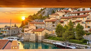 Un village côtier avec des bâtiments en pierre, un port de plaisance et des bateaux.