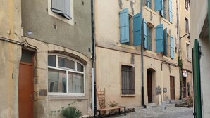 Una stretta strada acciottolata con edifici caratterizzati da finestre ad arco e persiane.