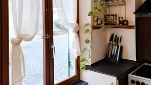 Una cucina con un fornello, pensili e una finestra con tende.