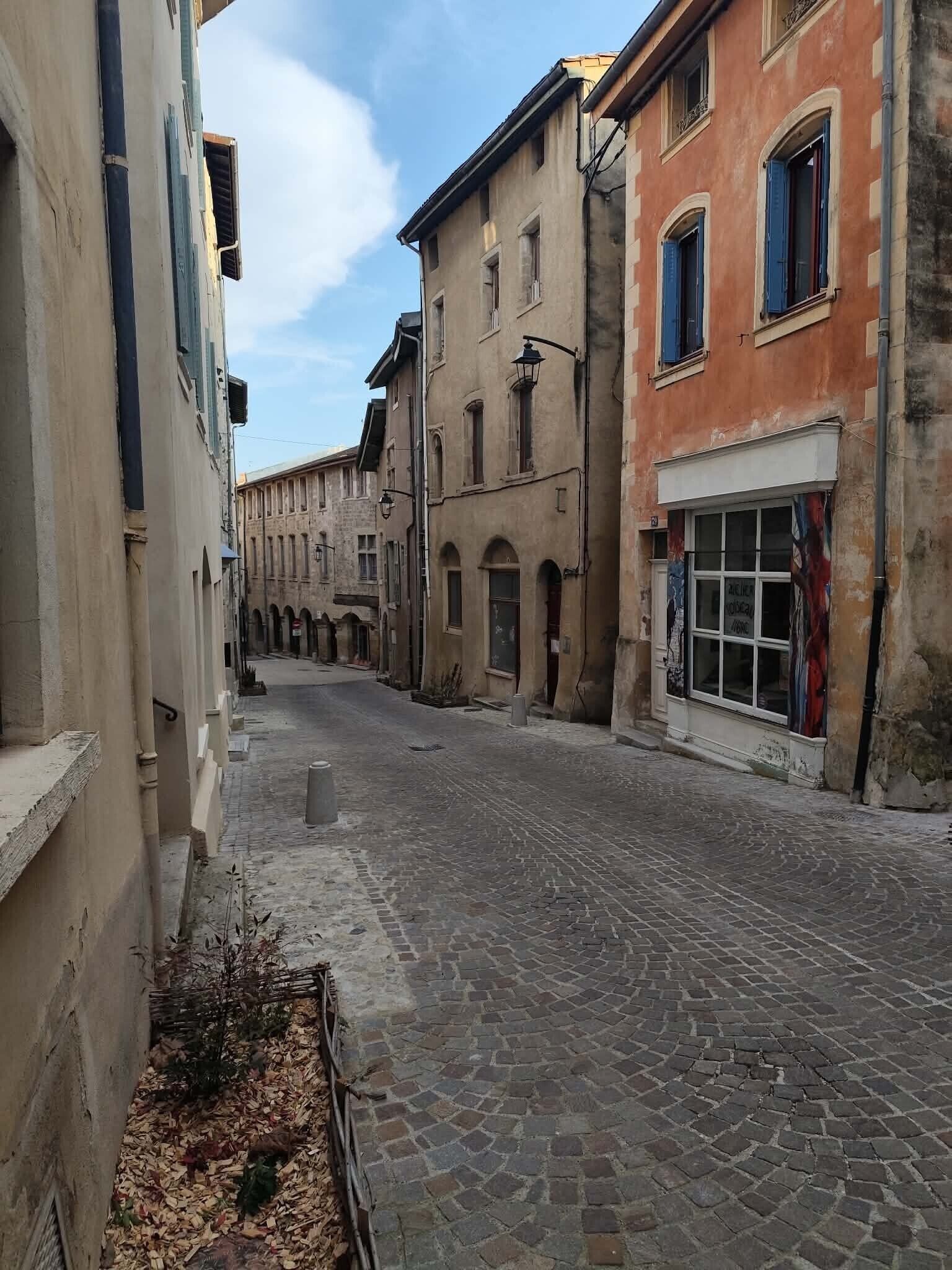 Une ruelle étroite pavée, bordée de bâtiments historiques, où se côtoient différents styles architecturaux, et au-dessus, un ciel dégagé.