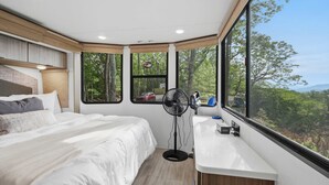 A bedroom with a bed, a standing fan, a window, and a sink. - The Chestnut- Smoky Mountains Tiny House w/ Hot Tub & Lake (Tallassee)