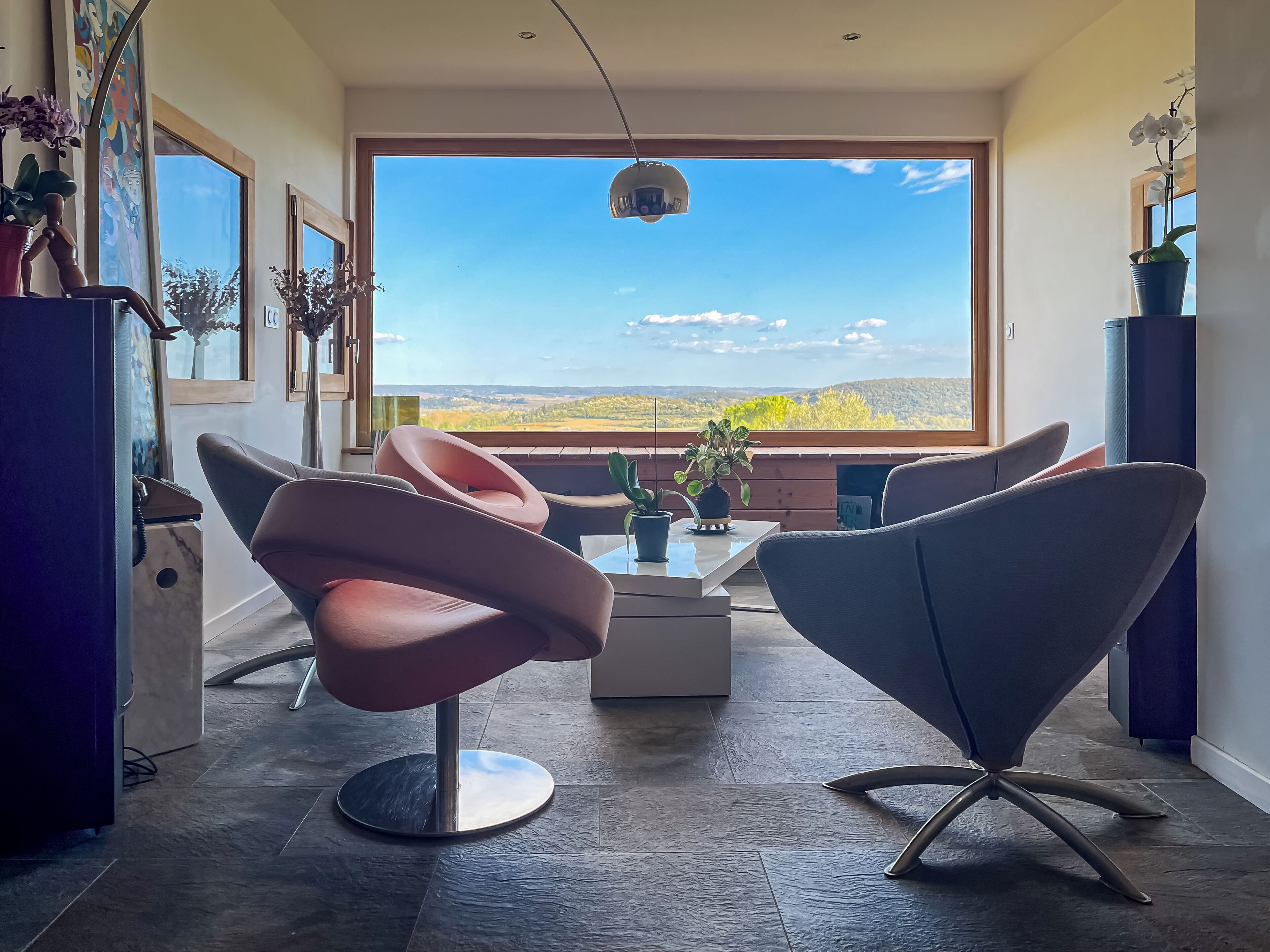 Ein moderner Essbereich mit großem Fenster, einer Deckenleuchte und Blick auf eine Landschaft.