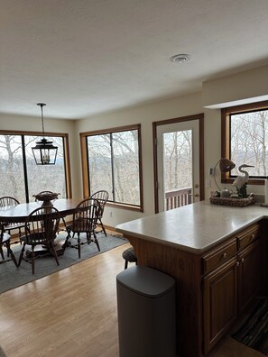 A spacious kitchen with a large island, wooden cabinetry, and a dining area with a table and chairs.