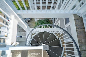Eine Wendeltreppe mit weißer Geländer, die zu einem Deck mit Holzboden und einem Blumentopf führt.