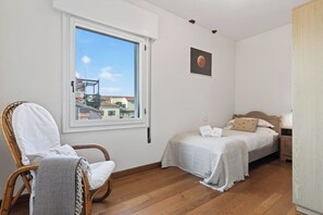 A bedroom with two beds, a window, a chair, and a wall-mounted picture. - Dimora San Leonardo (Venezia)