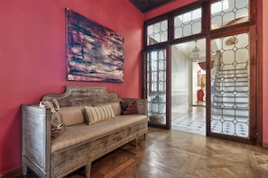 A room with a wooden sofa, a large abstract painting, and a view through a glass door with a geometric pattern. - Luxury 4 bedrooms apartment (Venezia)