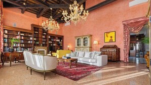 A spacious living room with a white sofa, a red rug, and a chandelier. - Dimora San Leonardo (Venezia)