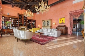 A spacious living room with a white sofa, a red rug, and a chandelier. - Dimora San Leonardo (Venezia)