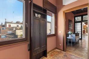 A hallway with a wooden cabinet, a window, and a view of rooftops. - Dimora San Leonardo (Venezia)
