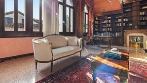 A room with a sofa, a coffee table, a bookshelf, and a fireplace. - Dimora San Leonardo (Venezia)