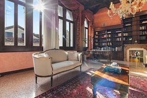 A room with a sofa, a coffee table, a bookshelf, and a fireplace. - Dimora San Leonardo (Venezia)