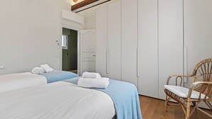 A bedroom with two beds, a wardrobe, a chair, and a door leading to another room. - Dimora San Leonardo (Venezia)