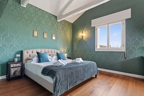 A bedroom with a bed, a nightstand, a wall-mounted light, and a window. - Luxury 4 bedrooms apartment (Venezia)