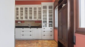 A kitchen with white cabinets, a tiled backsplash, and a stone-patterned floor. - Dimora San Leonardo (Venezia)