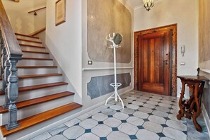 A staircase with wooden steps and a balustrade, a coat stand, a wooden door, and a patterned floor. - Dimora San Leonardo (Venezia)