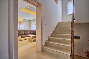 Eine Treppe führt zu einer zweiten Etage, einem Wohnzimmer mit Sofa und Couchtisch, und einer Tür zu einem weiteren Raum.