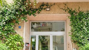 Entrada de edifício com porta de vidro, placa com o número 73 e uma pequena caixa de correio.