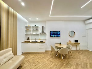 A modern kitchen with built-in shelves, a dining area with a round table and chairs, and a TV mounted on the wall. - Naples, Apartment up to 4 people, very close to Metro and Funiculars (Napoli)