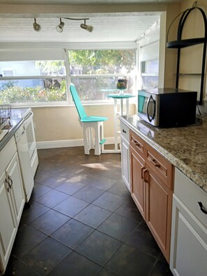 A kitchen with a dining area, a microwave, and a window with a view of greenery. - 2/1  St Pete 🏠-3 mi to Beach 1 mile to Downtown. New listing discounts (St. Petersburg)