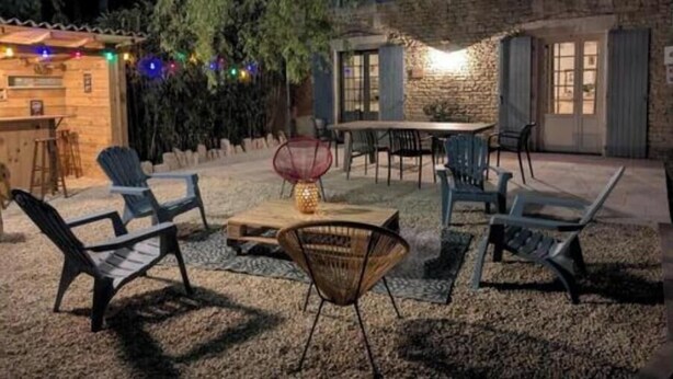Un patio al aire libre con asientos, una mesa y luces colgantes.