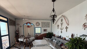 Un comedor con una mesa larga, sillas, una araña y vistas a través de un ventanal.