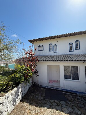 A traditional building with a tiled roof, a stone wall, and a small garden area.