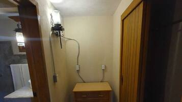 Un couloir étroit avec un banc en bois, une prise électrique fixée au mur et une porte sur la droite.