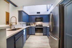 Una cocina moderna con armarios azules, electrodomésticos de acero inoxidable y un tragaluz.
