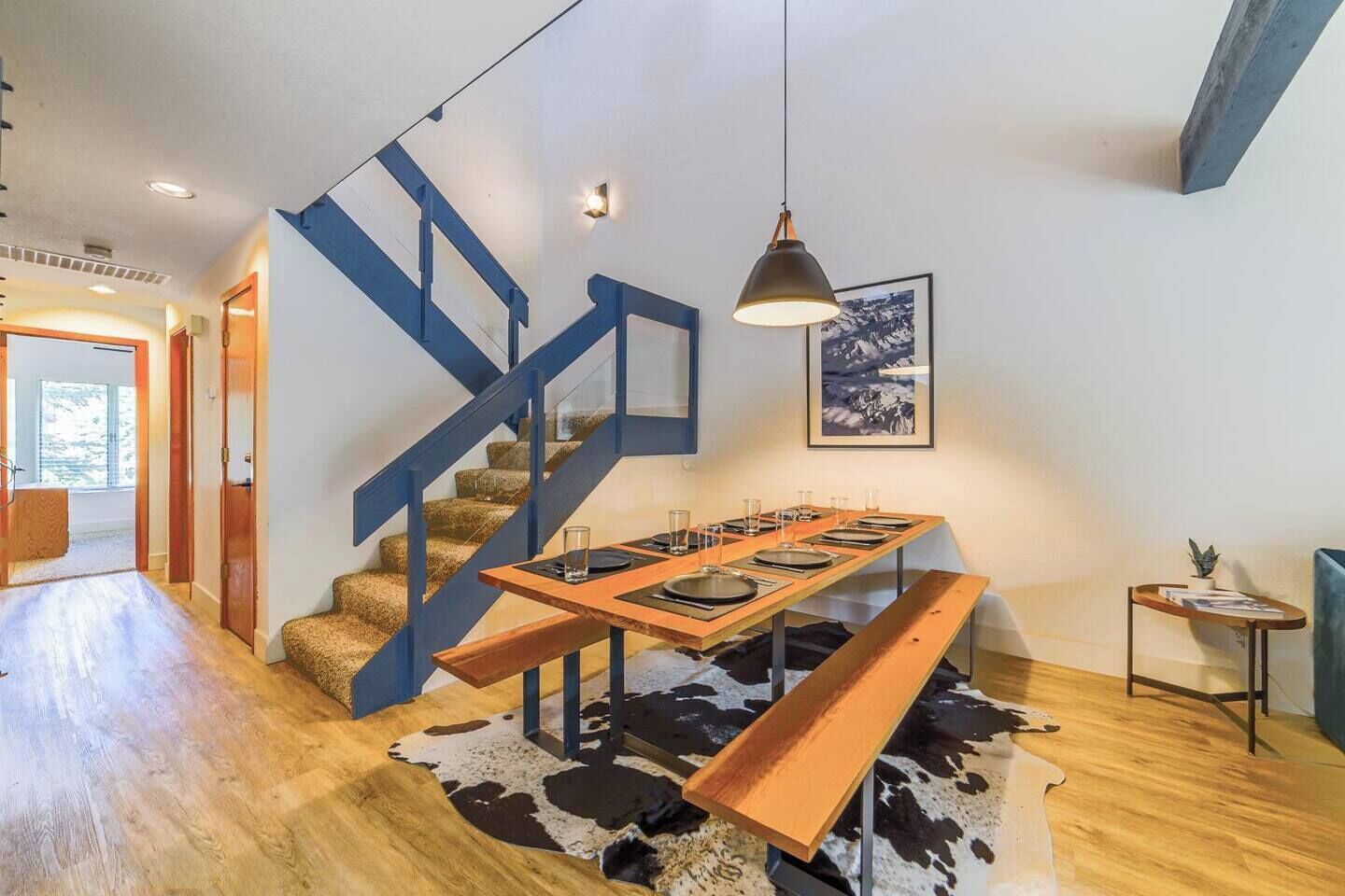 Un intérieur moderne avec un escalier, un coin repas et une petite table agrémentée d’une plante.