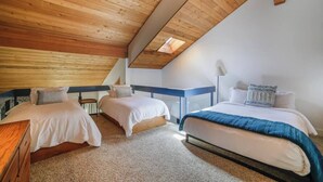 Een slaapkamer met twee bedden, een houten plafond en een dakvenster.