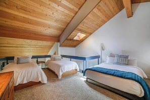 Un dormitorio con dos camas, techo de madera y tragaluz.