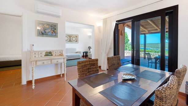 A dining area with a table, chairs, and a view through a glass door.