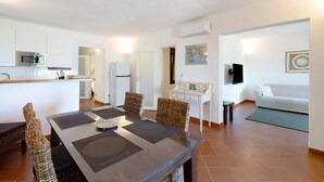 A modern living space with a dining area, kitchenette, and a sofa.
