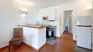 A compact kitchen with white cabinets, a built-in microwave, a stove, and a refrigerator.