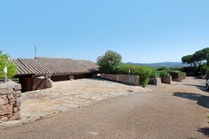A courtyard with a tiled-roof building, stone walls, and a gravel path. - Apartment 'Villa Solaris' with Sea View, Wi-Fi and Air Conditioning (Conca Verde)