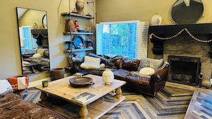 A cozy living room with a fireplace, a sofa, a coffee table, and a bookshelf.