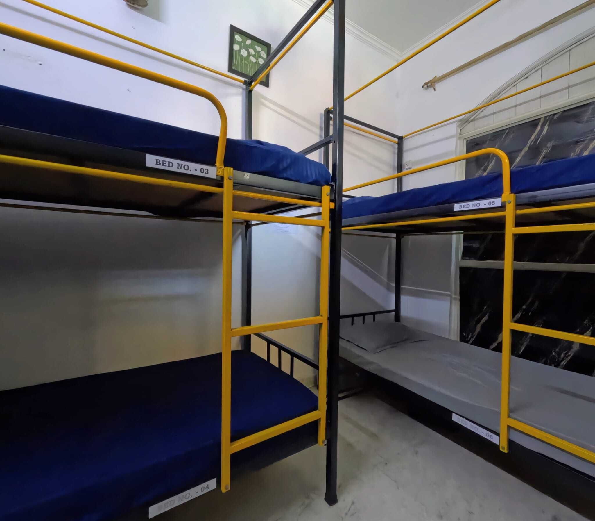 Bunk beds with metal railings, labeled with bed numbers, in a room with white walls and a window.