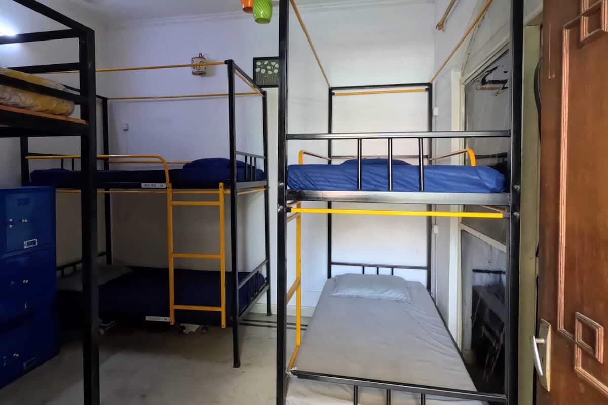 A dormitory room with bunk beds, a ceiling fan, and a door.