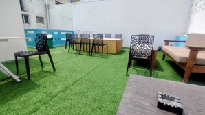 Una habitación con suelo de césped artificial, una mesa de madera y varias sillas de diseños elaborados.