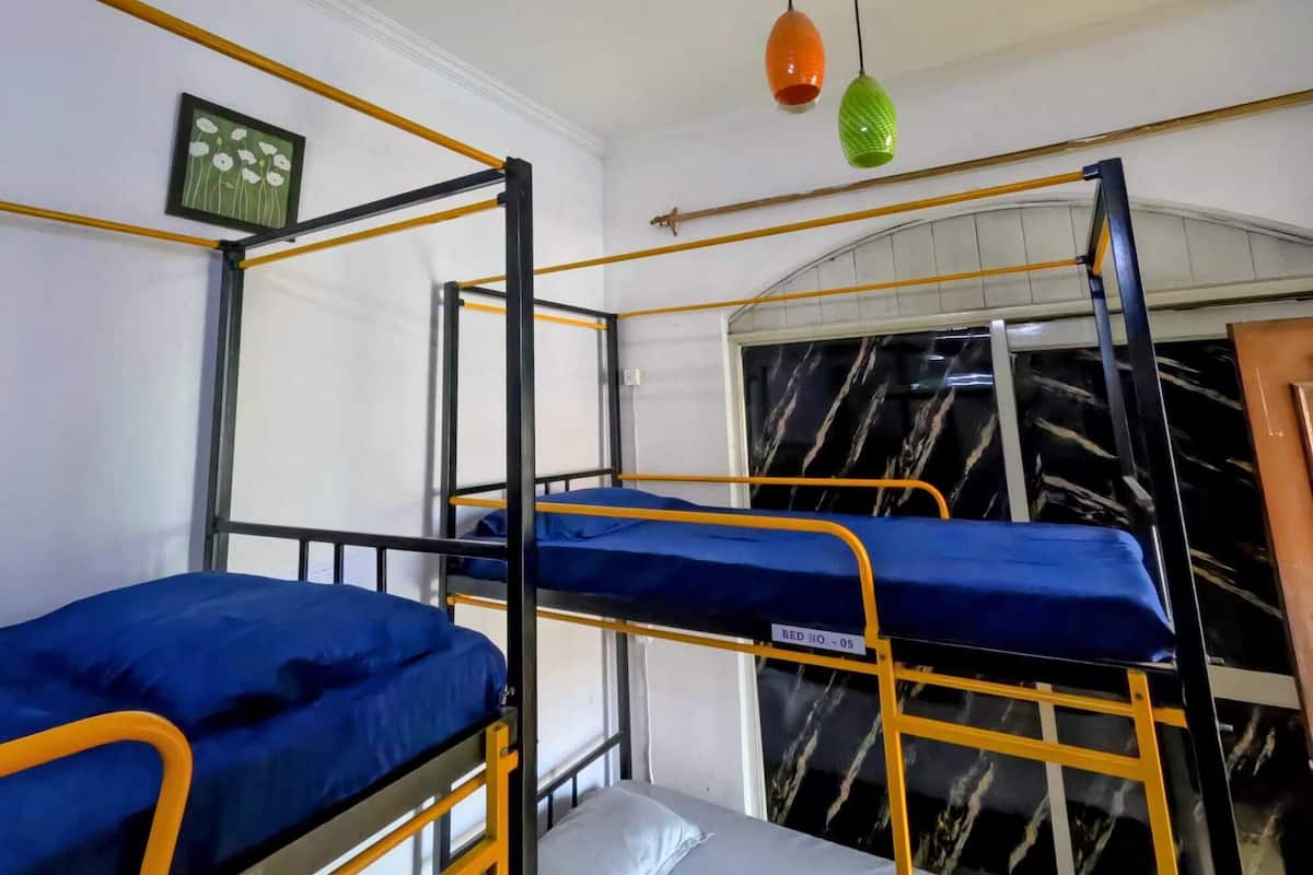 A bunk bed room with a window, a framed picture, and a ceiling light fixture.