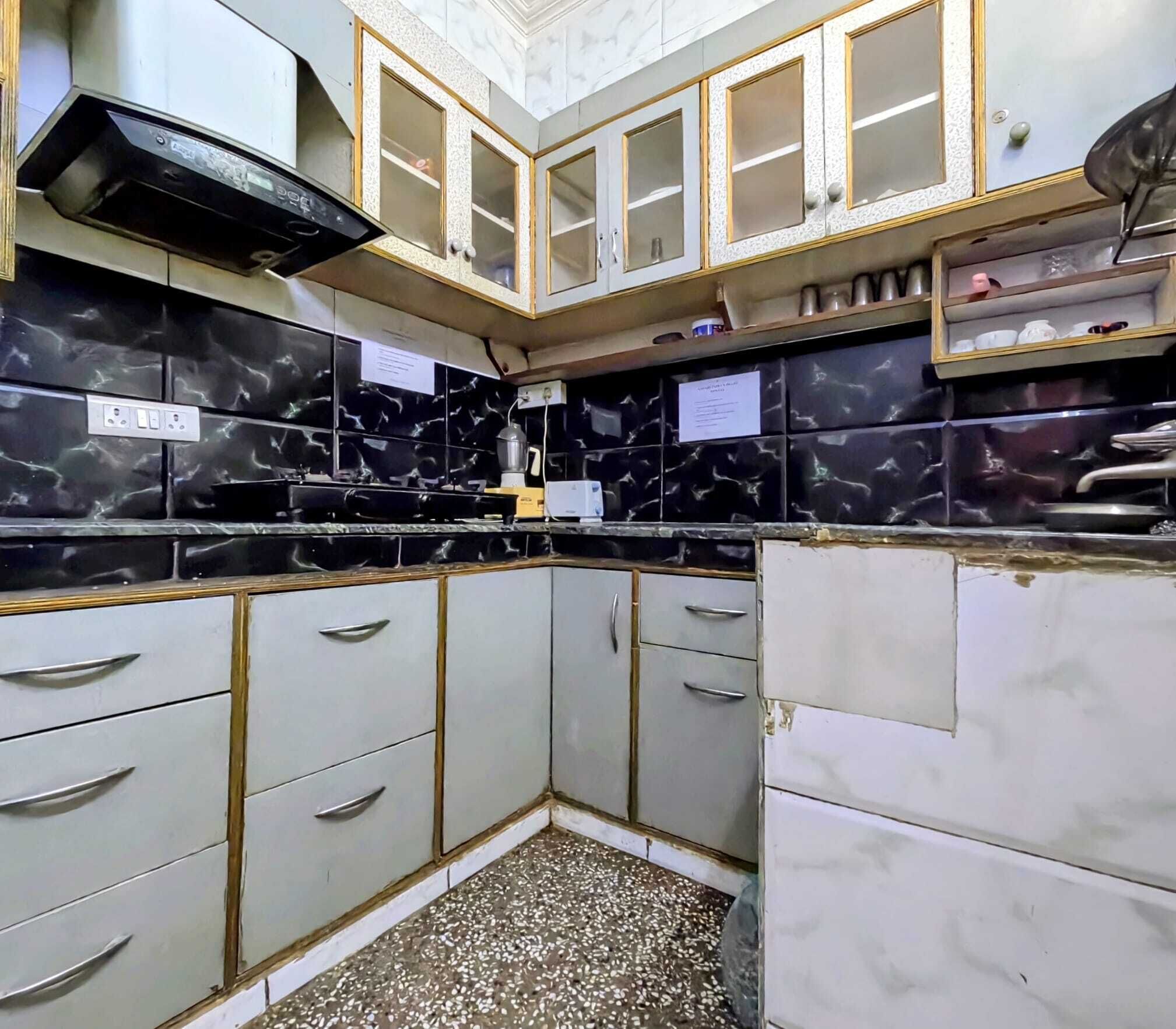 A kitchen with black marble tiles, white cabinets, and a built-in stove.